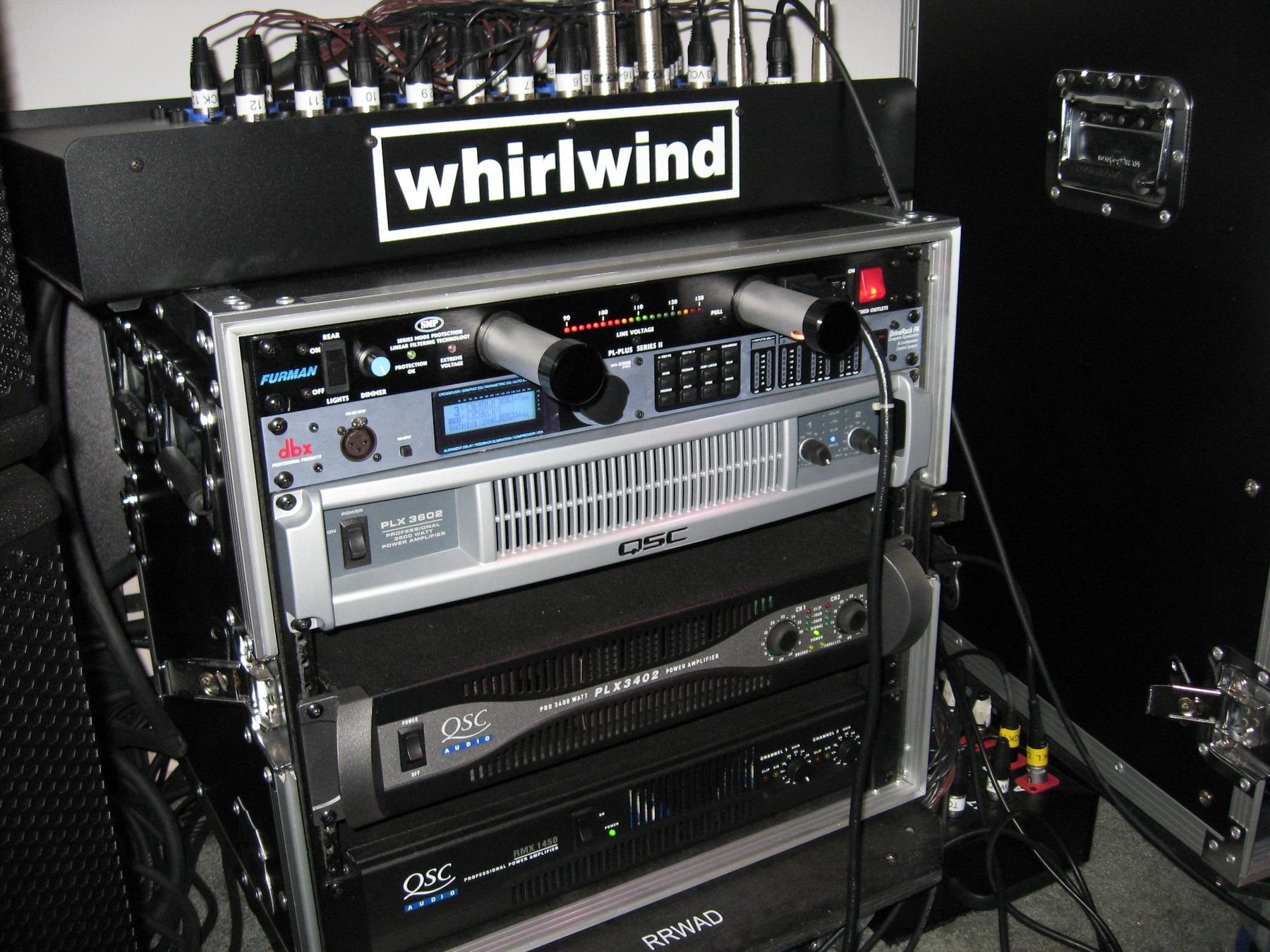 A rack of QSC amplifiers under a Whirlwind splitter
