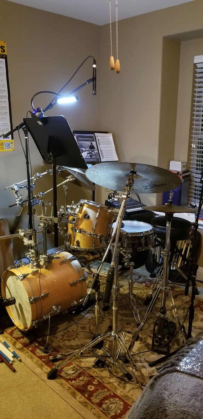 A small jazz kit in the corner of a room, lit by a desk lamp