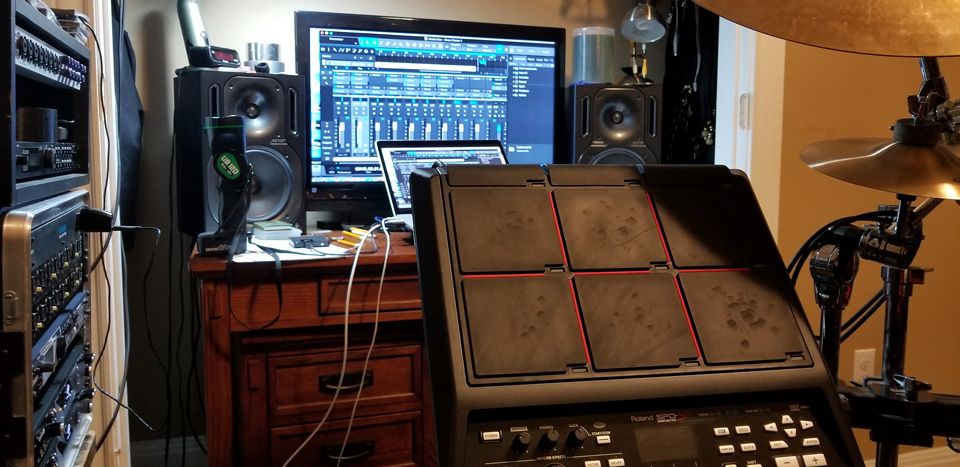 A recording desk with a laptop and a drum pad
