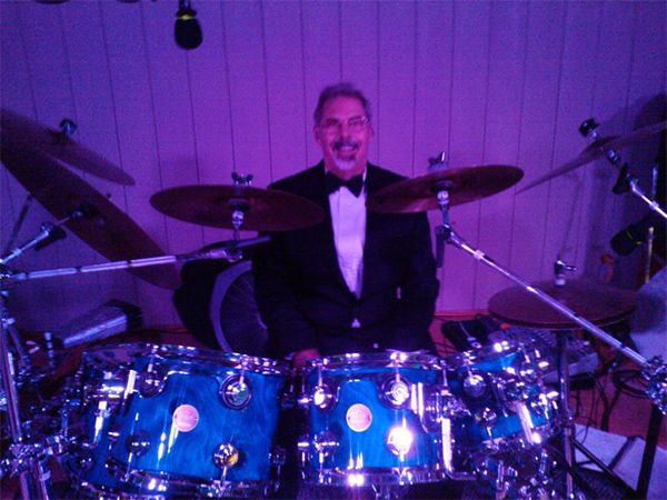 Bruce in a tuxedo behind the kit, purple light
